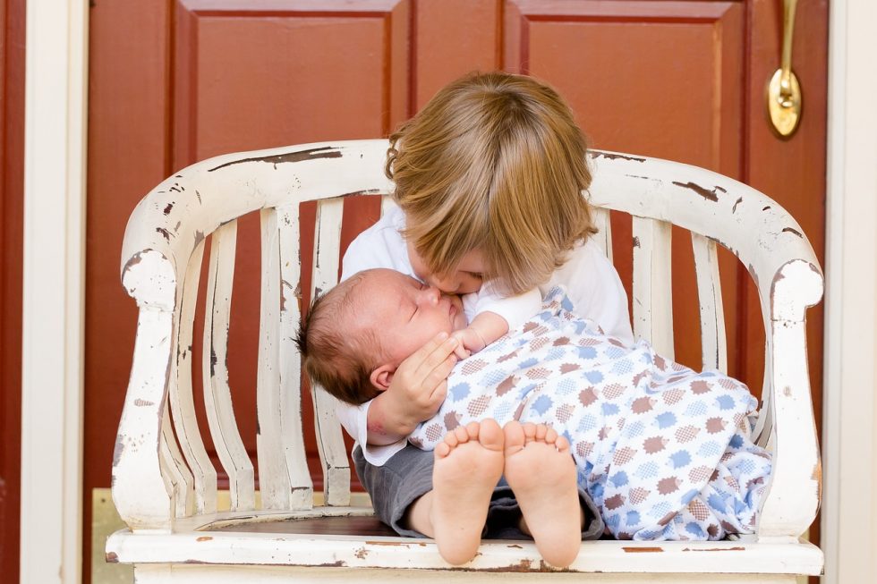 子どもが赤ちゃんを抱っこしている画像